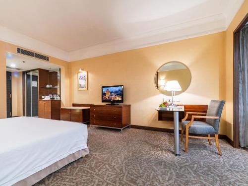 a hotel room with a bed and a desk and a mirror at Millennium Harbourview Hotel Xiamen-Near Metro Station & Zhongshan Road in Xiamen
