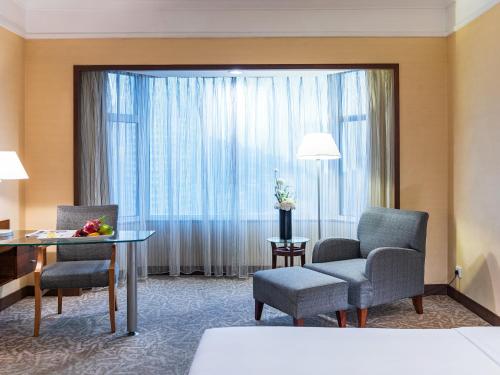 a hotel room with a table and chairs and a large window at Millennium Harbourview Hotel Xiamen-Near Metro Station & Zhongshan Road in Xiamen