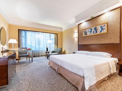a hotel room with a large bed and a desk at Millennium Harbourview Hotel Xiamen-Near Metro Station & Zhongshan Road in Xiamen
