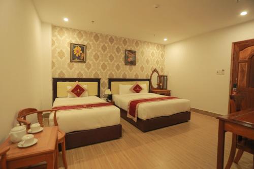 a hotel room with two beds and a table at Hoang Son Hotel - Can Tho in Can Tho