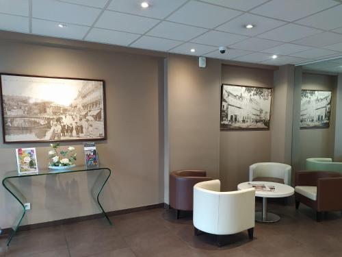 a waiting room with a glass table and chairs at BRIT HOTEL Confort Le Limouzi TULLE in Tulle