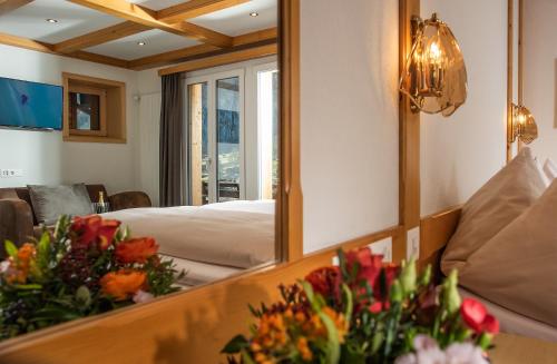 a mirror in a room with a bed and flowers at Hotel Silberhorn in Lauterbrunnen