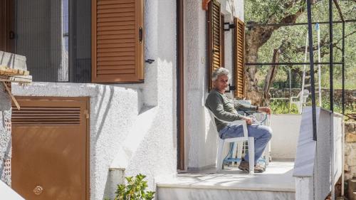 a man sitting in a chair outside a window at Stella Rooms in Kardamili