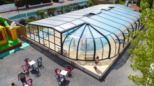 an image of a swimming pool in a green house at CAMPING PARADIS Domaine Oyat in Le Fenouiller