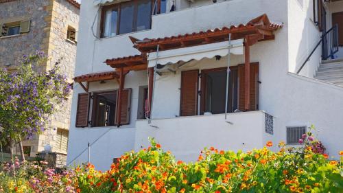 a white building with wooden windows and flowers at Stella Rooms in Kardamili