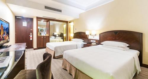 a hotel room with two beds and a flat screen tv at Millennium Harbourview Hotel Xiamen-Near Metro Station & Zhongshan Road in Xiamen