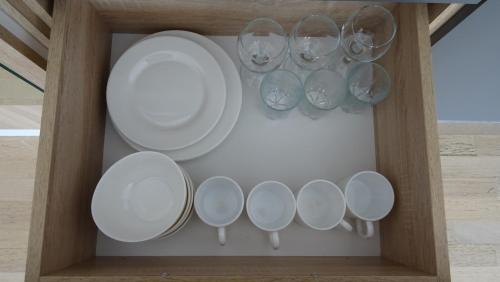 a cabinet with white plates and wine glasses at Green Apartments in Karpacz