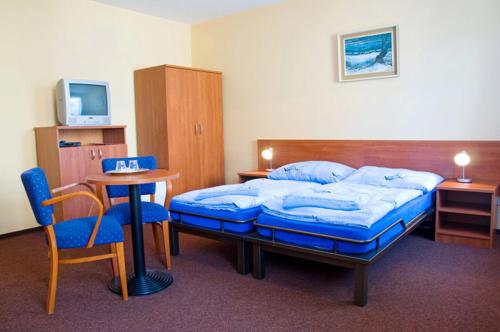 a hotel room with a bed and a table and chairs at Pension Marathon in Vrchlabí