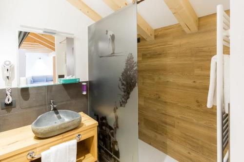 ソラーガにあるArnica Mountain Hotelの石造りの洗面台と木製の壁が備わるバスルーム
