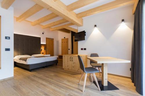 een slaapkamer met een bed, een bureau en een tafel bij Arnica Mountain Hotel in Soraga