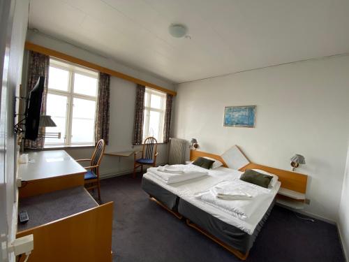 a bedroom with a bed and a desk and a table at Løgstør Badehotel - Hotel du Nord in Løgstør