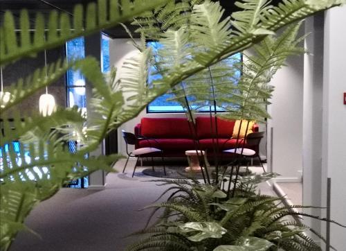 a red couch in a room with plants at Birkebeineren Hotel & Apartments in Lillehammer