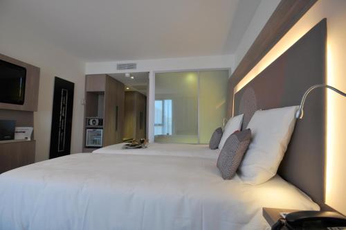 a bedroom with a large white bed with a lamp at Novotel Avignon Centre in Avignon