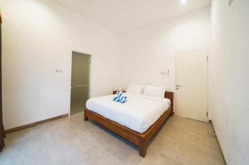 a bedroom with a bed with white sheets and blue pillows at Umaja Villa in Seminyak