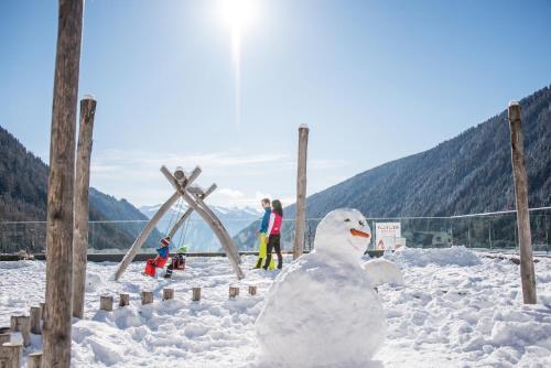 a snowman in the snow with people in the background at Familienhotel Huber in Valles