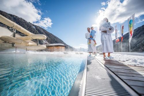 a group of people standing next to a swimming pool at Familienhotel Huber in Valles