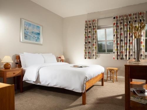 Un dormitorio con una gran cama blanca y una ventana en Faithlegg Self Catering Mews, en Waterford