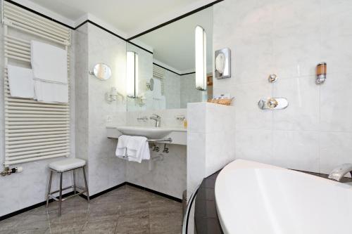 uma casa de banho branca com um lavatório e um espelho em Schweizerhaus Swiss Quality Hotel em Maloja