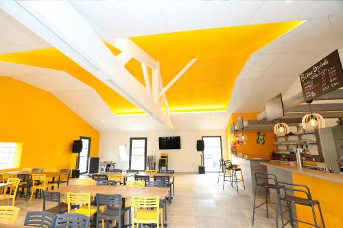 a restaurant with yellow walls and tables and chairs at CAMPING PARADIS Domaine Oyat in Le Fenouiller
