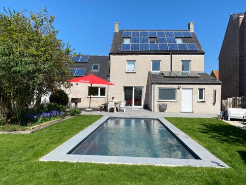 a house with a swimming pool with solar panels on its roof at De Lanterfanters Vakantiehuis Jef in Nieuwpoort