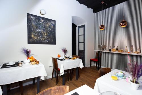 a restaurant with white tables and chairs and a painting on the wall at Babbu Hotel in Bastia