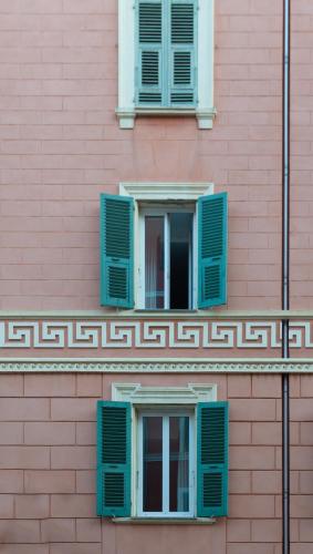 a pink building with two windows with green shutters at Babbu Hotel in Bastia