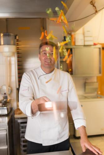 a chef standing in a kitchen with his arms crossed at Appartements-Restaurant Schwaiger in Tauplitz