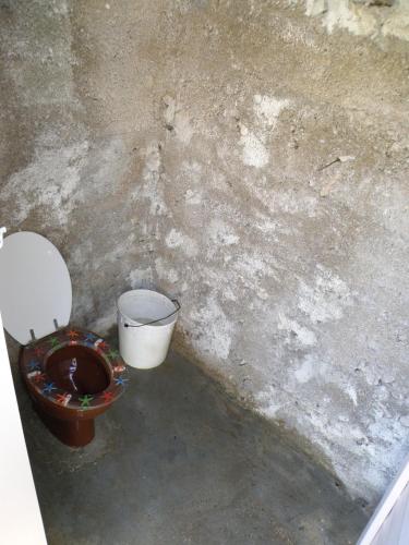 a dirty bathroom with a toilet and a bucket at Lošinj house robinson Vinodarska, Island Lošinj in Nerezine