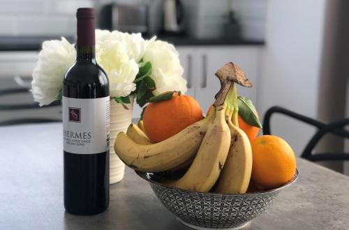 a bowl of bananas and oranges next to a bottle of wine at Sophia's Seaview Luxury Villas in Paphos City