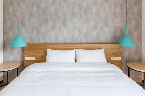 a bedroom with a white bed and two tables at Meets Anping in Tainan