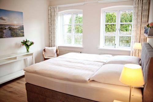 um quarto com uma cama branca e 2 janelas em Ferienwohung Tilla em Scharbeutz