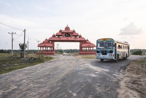 a bus driving down a road in front of a gate at Thambu Illam in Jaffna