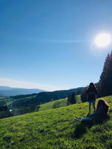 a person standing on a hill with a person laying on the grass at Alpenpension Gasthof in Ratten