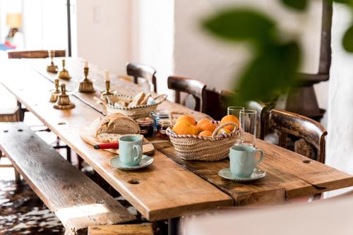 un tavolo di legno con sopra cesti di arance e tazze di Casa do Xão a Serpa