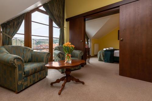 a hotel room with a couch and a table with flowers at Darovanský Dvůr - Wellness & Golf Hotel in Břasy