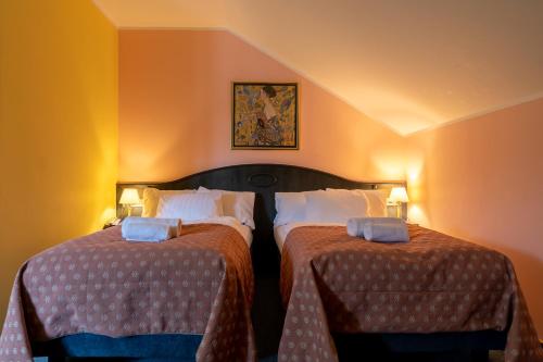 two beds in a room with orange walls at Darovanský Dvůr - Wellness & Golf Hotel in Břasy