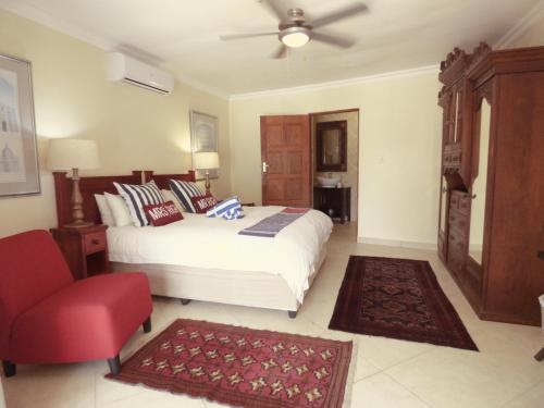 a bedroom with a white bed and a red chair at Turtle Bay Lodge in St Lucia