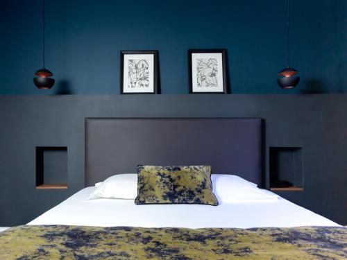 - une chambre avec un lit blanc et trois photos sur le mur dans l'établissement Babbu Hotel, à Bastia