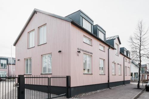 uma casa cor-de-rosa com uma cerca preta à frente. em Luxury Apartment Hovi em Naantali