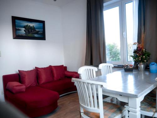 a living room with a red couch and a table at Hotel / Pension Villa Tanahlot in Zandvoort