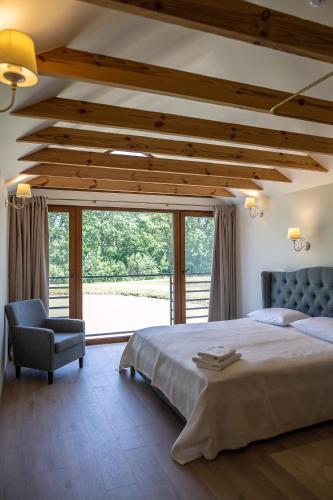 a bedroom with a large bed and a chair at Sodyba Pelėdų medus in Vainekoniai