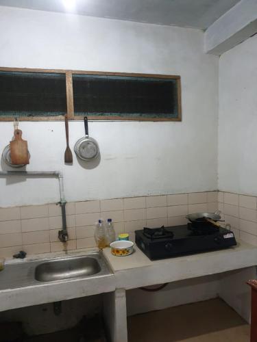 a kitchen counter with a sink and a stove at Homestay Mas Arjuna - Female Only in Bagongsabrangan