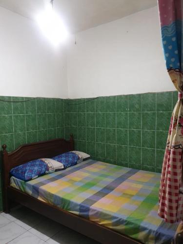 a bed in a room with a green tiled wall at Homestay Mas Arjuna - Female Only in Bagongsabrangan