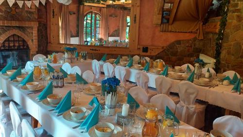 a long table with white tables and chairs in a room at Zajazd pod Chmurką in Rabka-Zdrój