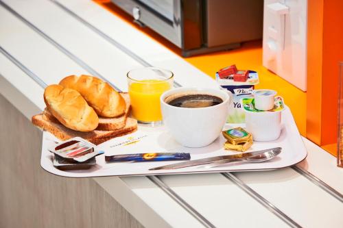 a breakfast tray with coffee and croissants and toast at Premiere Classe Caen Nord - Mémorial in Caen