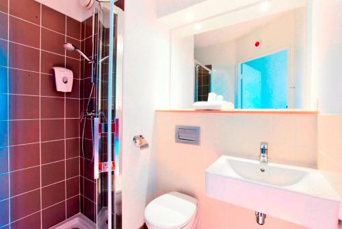 uma casa de banho com um lavatório, um WC e um espelho. em Premiere Classe Caen Nord - Mémorial em Caen