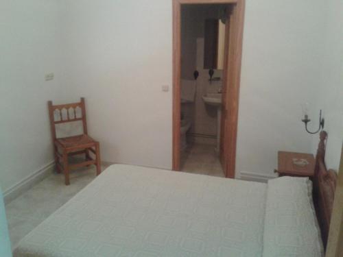 a bedroom with a bed and a chair and a bathroom at Hostal Restaurante Los Bronces in Riópar