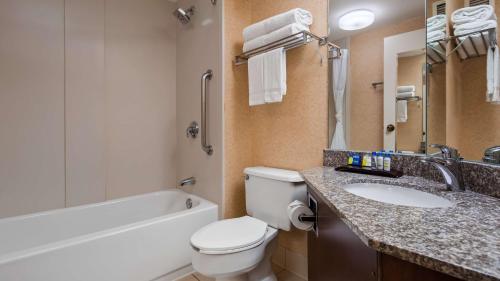 a bathroom with a toilet and a sink and a bath tub at SureStay Plus Hotel by Best Western Chicago Lombard in Lombard