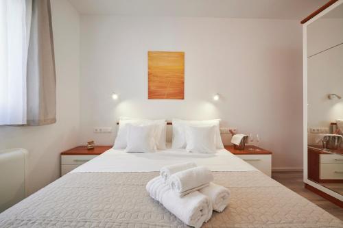 een slaapkamer met een wit bed en handdoeken bij Apartmani Laurus in Trogir