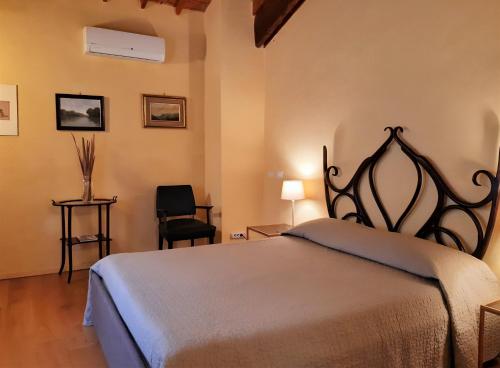 een slaapkamer met een bed en een stoel bij B&B Le Stanze del Belriguardo in Voghiera